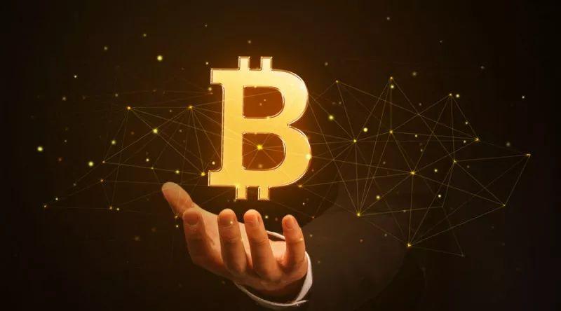 The Bitcoin logo displayed prominently on a screen with fluctuating price charts in the background